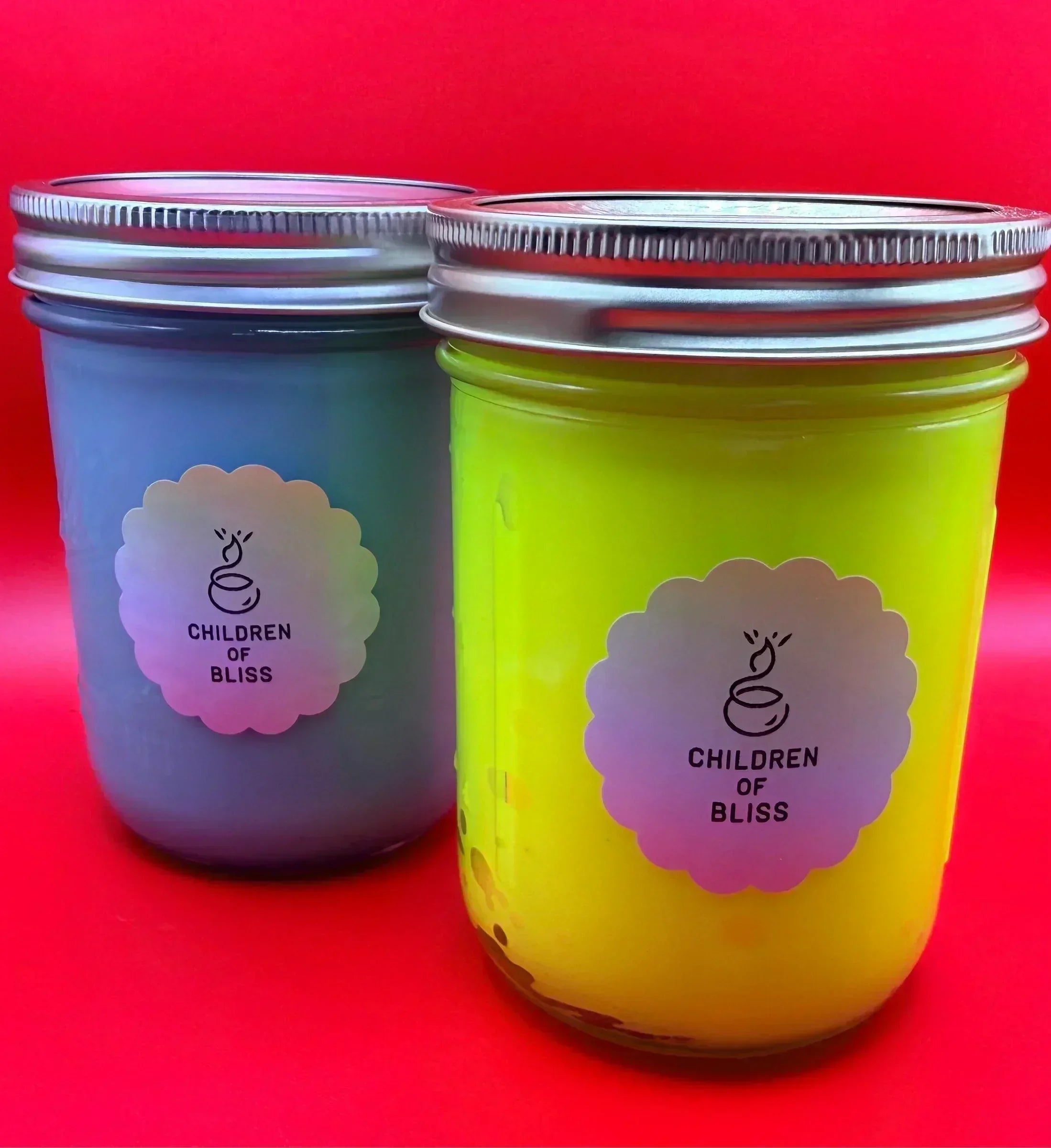 Custom Children of Bliss candles in colorful tins on vibrant red background