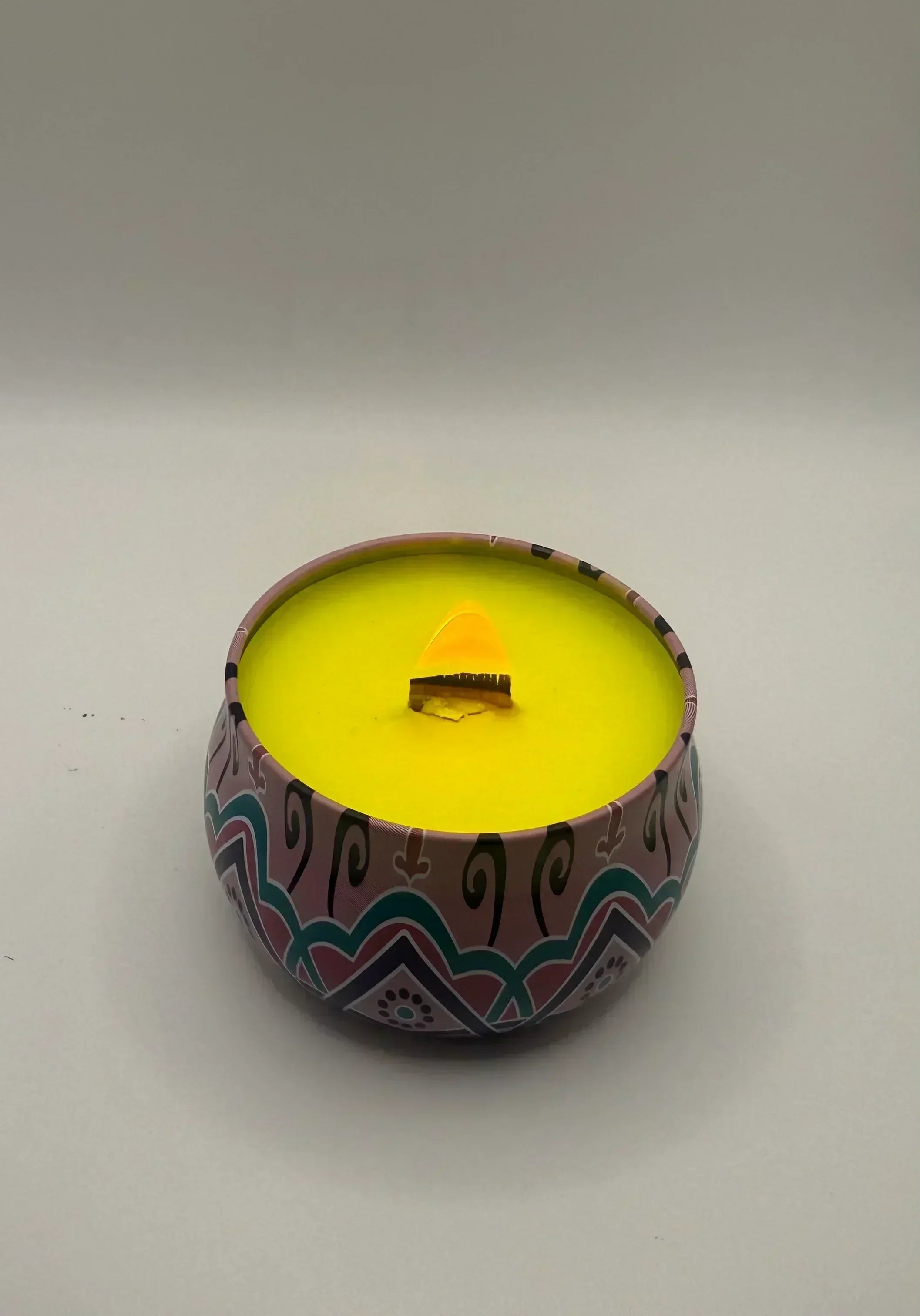 Yellow custom candle in decorative tin from Children of Bliss Candle co, on plain background