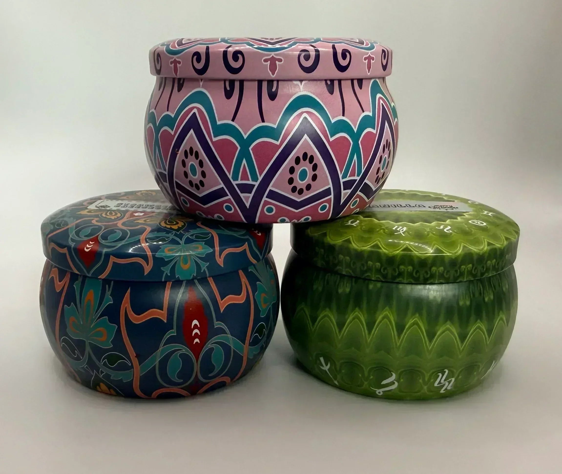 Three colorful decorative tin candles from Children of Bliss Candle co on a white background